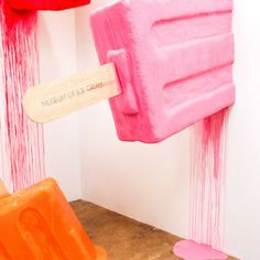 two popsicles are being sprayed with pink and orange paint in an art gallery setting