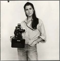 a black and white photo of a woman holding a camera in one hand and a video camera in the other