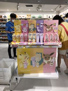 two people standing next to each other in front of shelves with pokemon merchandise on them