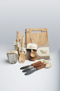 wooden utensils and other kitchen items are arranged on a white surface with a cutting board