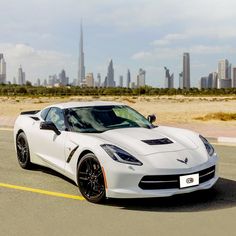 a white sports car parked in front of a city skyline