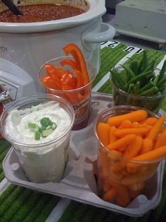 carrots, celery, green beans and dip in plastic containers on a table