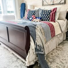 a bed with an american flag comforter and pillows on top of it in a bedroom