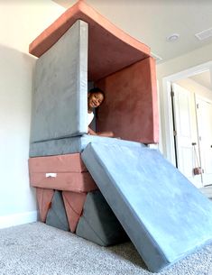 a young boy is playing in a cardboard house made to look like a giant piece of furniture