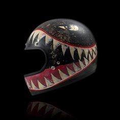 a helmet with an animal's mouth painted on the front and side, against a black background