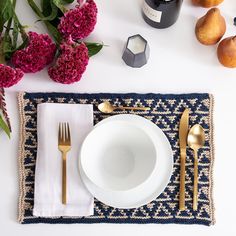 the place setting is ready to be served with flowers and fruit on the tablecloth