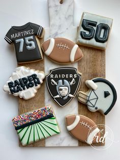 decorated cookies are arranged in the shape of footballs and jerseys on a cutting board