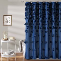 a blue shower curtain with black flowers on it in a white room next to a table and chair