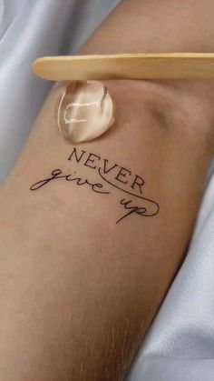 a person with a tattoo that says never give up on their arm and the word is in cursive writing