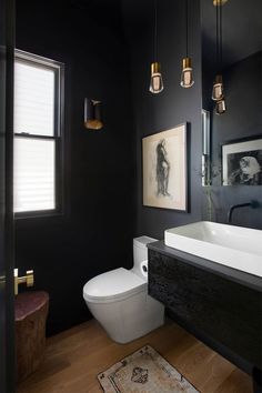 a white toilet sitting next to a sink in a bathroom on top of a hard wood floor