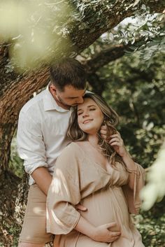 a man and woman standing next to each other under a tree