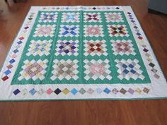 a green and white quilt sitting on top of a wooden floor