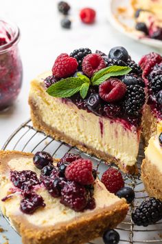 a cheesecake with berries on top is sitting on a cooling rack next to another piece of cake