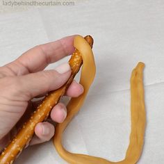 a person holding a long piece of food in their left hand and the end of a banana shaped cookie