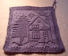 a purple crocheted dishcloth with a house on the front, and a tree on the back