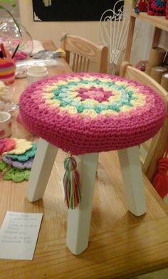 a crocheted stool sitting on top of a wooden table