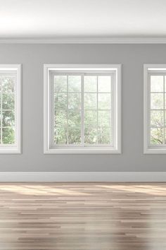 an empty room with three windows and hard wood flooring