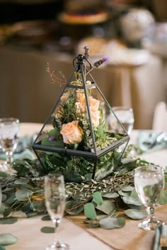 an arrangement of flowers and greenery on a table