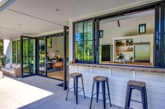 an outdoor bar with three stools next to it on the side of a house