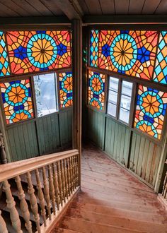 the sun shines through stained glass windows in an old building's staircase area