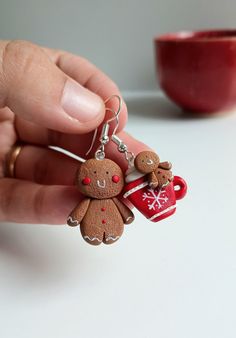 a person is holding two gingerbread cookies in front of a red cup and bowl