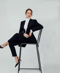 a woman sitting on top of a metal chair wearing a black suit and white shirt