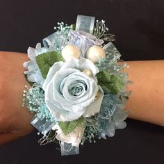 a wrist corsage with blue flowers and pearls