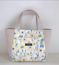 a yellow and blue flowered bag sitting on top of a white table next to a wall