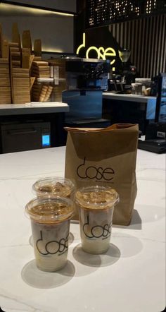 three cups and a brown bag on a counter