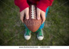 a person holding a football in their hands on the grass, looking down at it