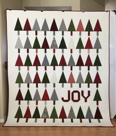 a quilted christmas tree with the word joy written on it in red, green and grey