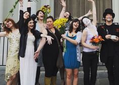 a group of people standing next to each other in front of a building with flowers