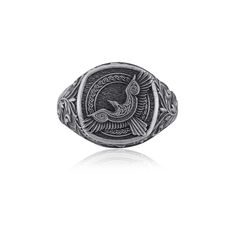 a silver ring with an image of a bird on the front and side, sitting on a