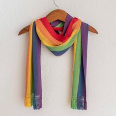 a multicolored scarf hanging on a white wall next to a wooden hanger