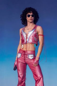 a woman in pink leather pants and cropped top posing with her hands on her hips