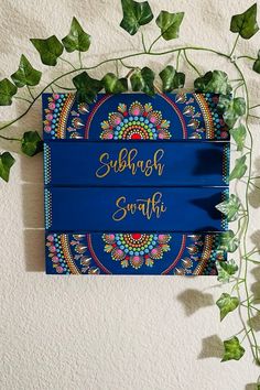 a blue sign with gold lettering on it next to some green leaves and ivys