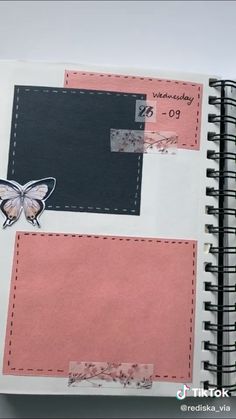 an open planner book with butterfly stickers on the cover and pink paper around it