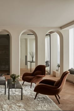 a living room filled with lots of furniture next to tall arched windows on either side of the wall