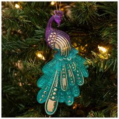 a peacock ornament hanging from a christmas tree