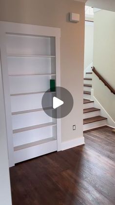 an empty room with stairs and white bookcases on the wall next to a wooden floor