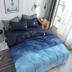 a bed with blue comforter and pillows in a white room next to a window