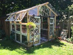 a small wooden greenhouse sitting in the middle of a yard