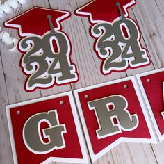 red and silver graduation decorations on a white wooden table with the letters grad spelled out