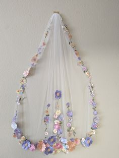 a wedding veil hanging on the wall with flowers attached to it's back end