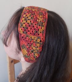 a woman with long hair wearing a crocheted headband on top of her head