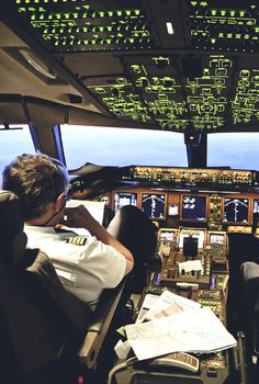 two pilots are sitting in the cockpit of an airplane looking at the flight manuals