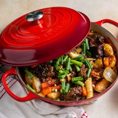 a red pot filled with food next to two bowls full of rice and other foods