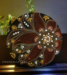 an artistically painted rock sitting on top of a wooden table next to a potted plant