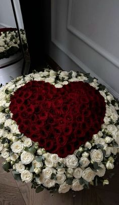 a heart - shaped arrangement of white and red roses sits in front of a mirror