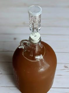 an empty brown glass bottle on a white wooden table with a clipping in the top